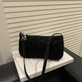 Detail einer schwarzen Schultertasche mit Leopardenmuster und schmalem Riemen auf Buch - Schwarz