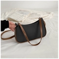 Nahaufnahme der schwarzen Leder-Schultertasche mit braunem Rand und silbernen Ringen - Schwarz