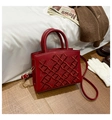 Macro detail of red quilted handbag featuring crown embroidery and gold-tone hardware - Red