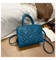 Blue patent leather bag detail with geometric patterns and floral embroidery on a floor - Blue
