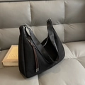 Minimalist black faux suede shoulder bag with wide nylon strap on grey leather sofa - Black