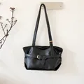 Detail of black leather bucket bag with decorative crisscross straps and metal eyelets - Black