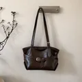 Detail view of brown vintage bucket bag with decorative strap and gold metal buckle - Brown