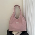 Minimalist purple corduroy tote bag with fashion label on a simple black desk background - Pink