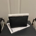 Pochette minimalista in pelle nera con bordo in peluche bianco su un supporto espositivo - Nero