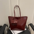 Large burgundy glossy leather tote bag with matching coin pouch on a designer chair - Red
