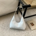 White hobo shoulder bag with textured finish and brand lettering on an elegant wooden chair - White