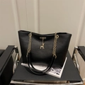 Borsa tote nera opaca con catena dorata e ciondolo a cervo su sedia moderna - Nero