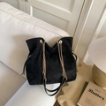 Minimalist black suede tote bag with gold chain strap and drawstring closure in home setting - Black