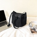 Minimalistische schwarze Wildleder-Beuteltasche mit Lederbesatz und Bommel auf weißem Bettzeug - Schwarz