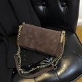 Borsa a tracolla in camoscio marrone con catena dorata e cuciture incrociate su sedia nera - Marrone