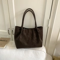 Dettaglio della borsa tote in pelle opaca marrone scuro con cucitura verticale sul divano - Caffè senza Ciondolo