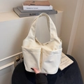 Minimalistische cremefarbene Eimertasche mit großen Fronttaschen und Tragegriff - Gebrochenes Weiß
