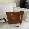 Minimalist brown large tote bag with slim straps on a white sofa in a cozy home setting - Tan