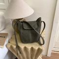 Detail view of a dark grey bucket bag with contrast white stitching on a wooden table - No Pendant / Green