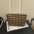 Pochette tissée à damier marron et beige sur un livre blanc dans un décor minimaliste - Marron
