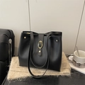 Bolso tote negro clásico con hebilla de metal dorado sobre fondo de bufanda beige - Negro