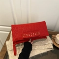 Red faux suede handbag with leopard pattern and golden rivets on beige knit background - Red