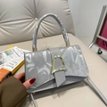 Grey crossbody bag with silver graffiti print and golden triangle buckle on a sofa - Gray