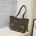 Detail of dark green tote bag featuring a cute cat face design and brown leather straps - Green