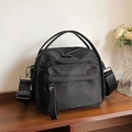Chic black multi-layer nylon crossbody bag with wide strap on a wooden shelf - Black