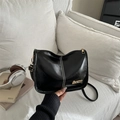 Schicke schwarze Vintage-Umhängetasche mit weißen Nähten und Goldlogo auf beigem Sofa - Schwarz