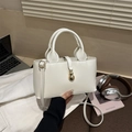 Close-up of white glossy patent leather handbag with elegant gold gourd-shaped hardware charm - White