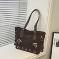 Detail of dark brown tote bag featuring cat pattern with gold metal hardware accents - Brown