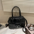 Glänzende schwarze Handtasche mit Schleife und Herzanhänger in einer Lifestyle-Umgebung - Schwarz