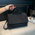 Large black matte shoulder bag with flap closure shown in a minimalist office setting - Frosted Black