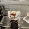 Mini white crossbody bag with red cherry charm and golden chain handle detail - White