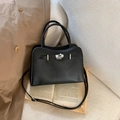 Dettaglio borsa a mano nera in pelle martellata con chiusura argento su sfondo di libri - Nero (Senza Ciondolo)