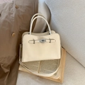 Dettaglio borsa in pelle crema con chiusura a scatto argento su un libro aperto - Bianco (Senza Ciondolo)