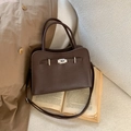 Detail of dark brown pebble leather bag with metal clasp on a vintage book backdrop - Coffee Without Pendant