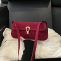 Sac baguette rétro français en daim bordeaux avec boucle dorée, porté à la main - Bordeaux