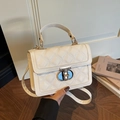 Weiße Stepptasche mit goldenem Schloss und Griff in einer Lifestyle-Umgebung gezeigt - Gebrochenes Weiß