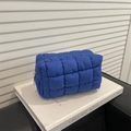Royal blue quilted puffer clutch bag with metallic zipper on a decorative book - Blue