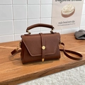 Bolso bandolera de cuero marrón oscuro con textura granulada, hebilla dorada y asa superior - Marrón