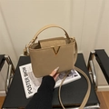 Elegante borsa a tracolla beige con fibbia a V dorata su sedia in pelle - Cachi