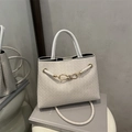 Weiße geflochtene Tragetasche mit goldenem Knotendetail und rundem Griff im Minimal-Stil - Gebrochenes Weiß