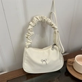 Sac sous le bras plissé crème chic avec détail nœud argenté sur une table en bois - Blanc