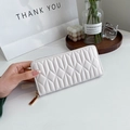 Close-up of white quilted long wallet with golden zipper and elegant stitching - White