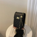 Detailed close-up of quilted black leather phone bag with gold chain and twist lock - Black