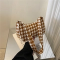 Detailopname van de houndstooth-textuur en schouderband van een vintage baguette-tas - Donkerbruin