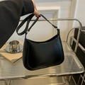 Detail of a black crescent hobo bag with smooth leather finish in a lifestyle setting - Black