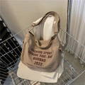 Khaki canvas crossbody bag with artistic letter print and wide strap in a shopping cart - Khaki