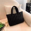 Chic black quilted puffer tote bag with soft padded handles on a minimalist background - Black