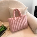 Detailed view of pink quilted handbag with soft padding on a cozy velvet sofa - Pink