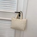 Detail van een crème gewatteerde tote bag aan een vintage deurklink - Wit