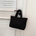 Detail van zwarte gewatteerde shopper met verticale stiksels hangend aan een handvat - Zwart